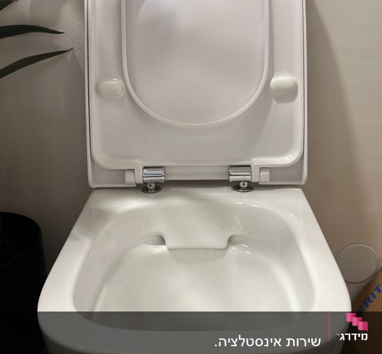 אסלה לבנה עם מכסה פתוח בחדר אמבטיה